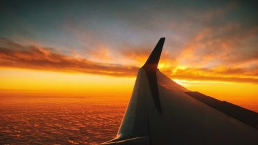 wing of a plane with the sunset in the background