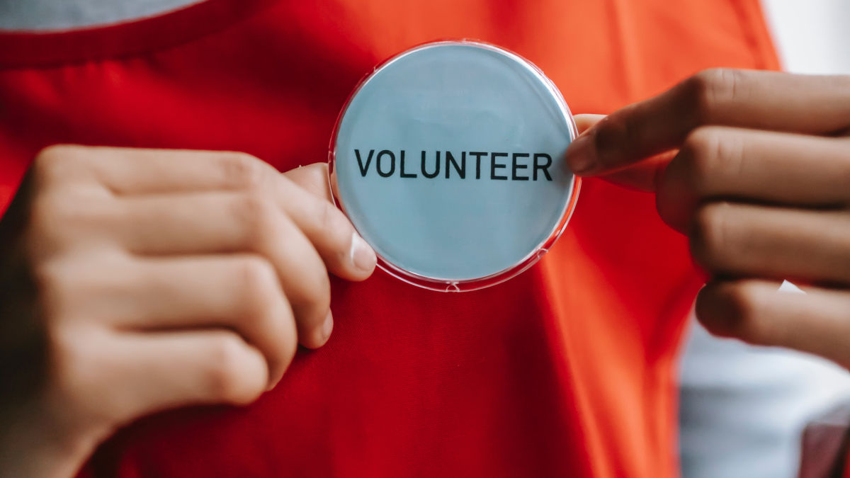 person wearing a round pin with the text "volunteer" on it