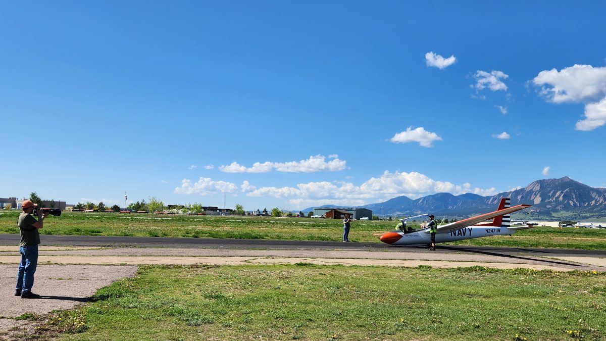 white and red glider plane in a large, open field