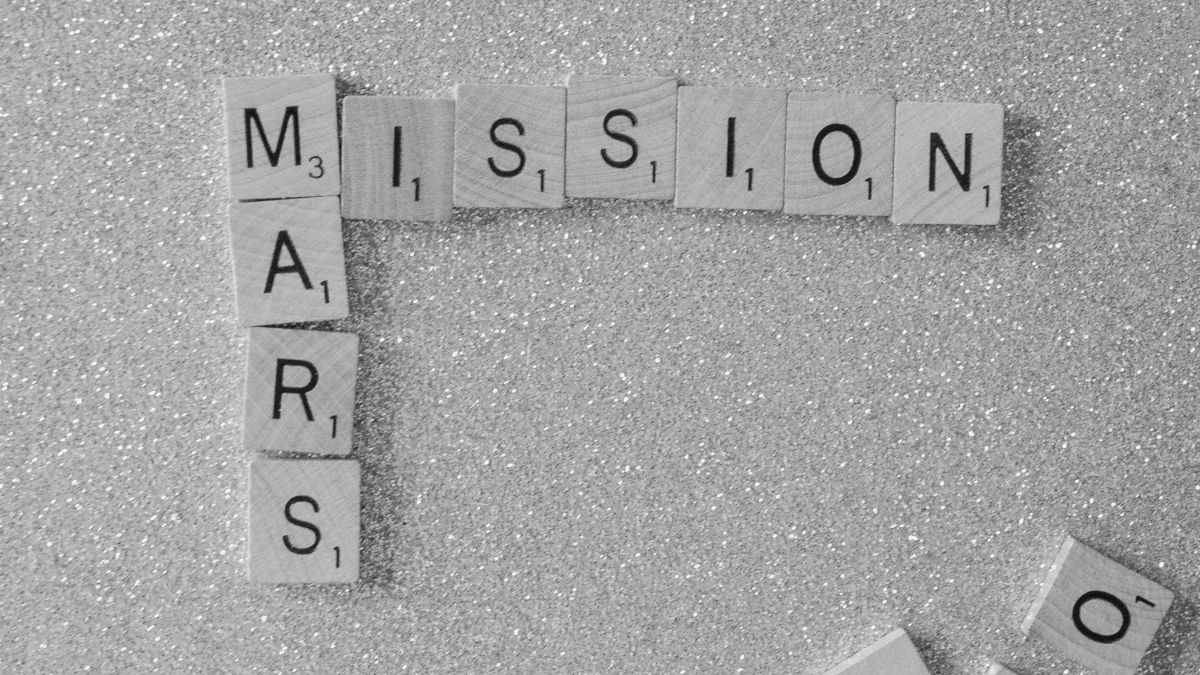 "mission mars" spelled out with scrabble tiles on a white glitter background