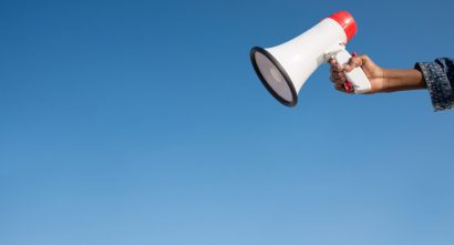 image of a white and red megaphone being held up with a blue sky in the background